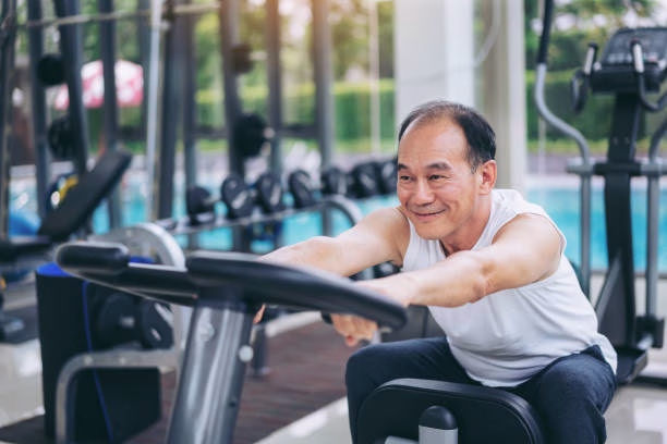 Senior man exercise on cycling machine in fitness center. Mature healthy lifestyle.