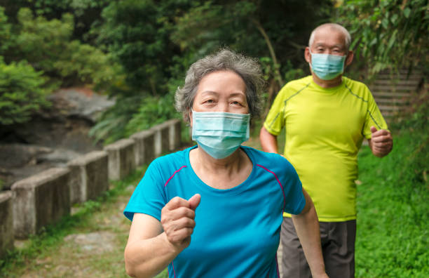 Senior couple wearing face mask and walking trough nature park
